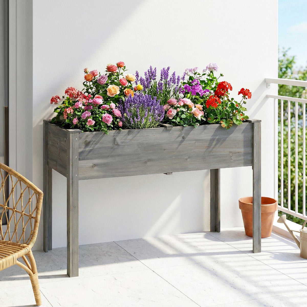 Grey raised bed on legs with red and pink flowers on a white balcony