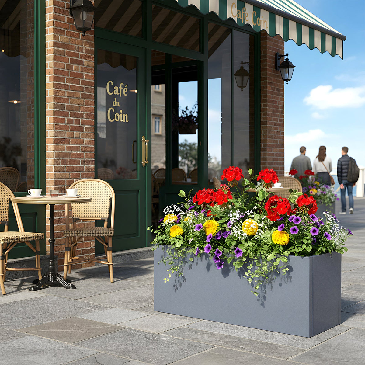 Grey metal planter with red and yellow flowers outside a café