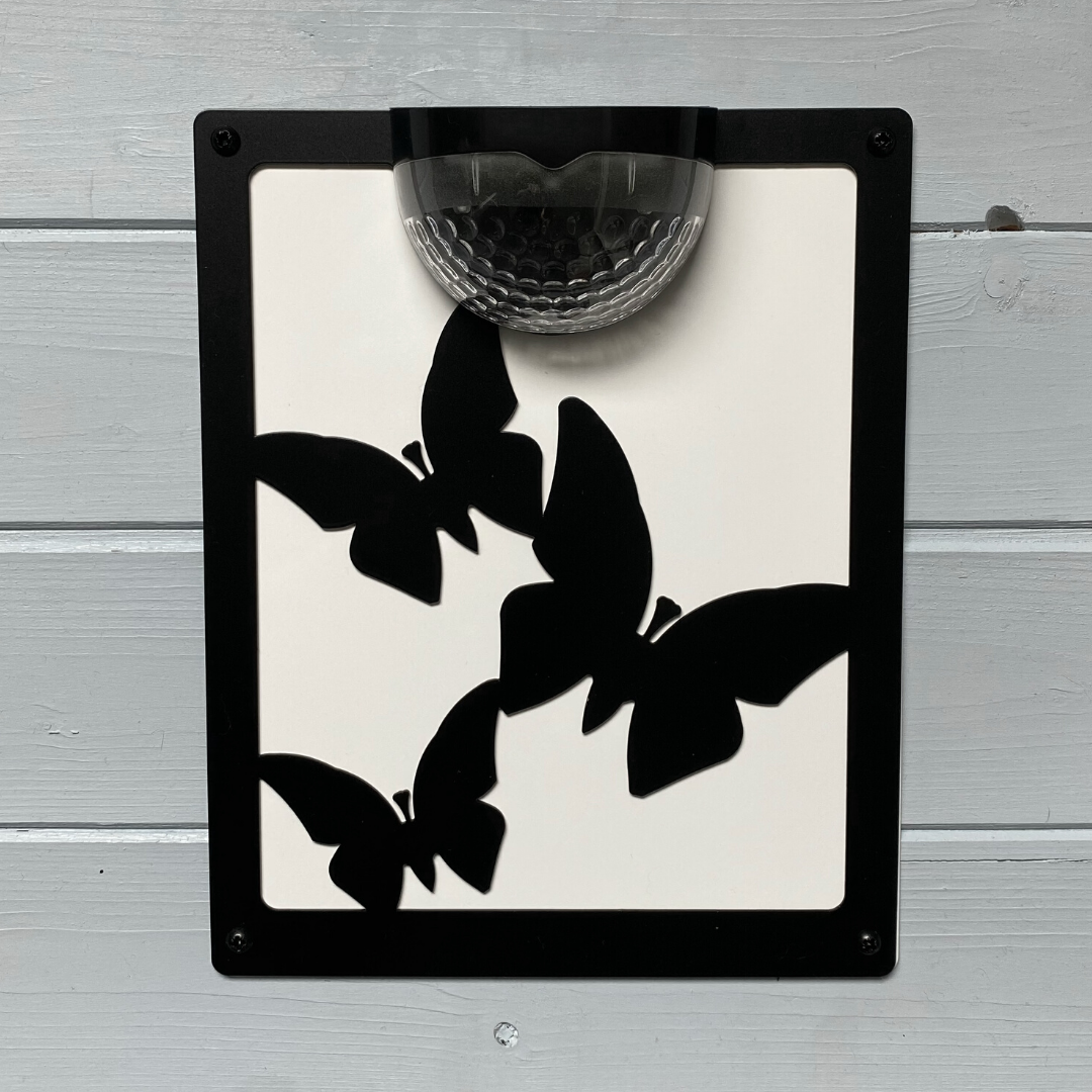 Butterfly solar plaque with white backing panel on white painted cladding
