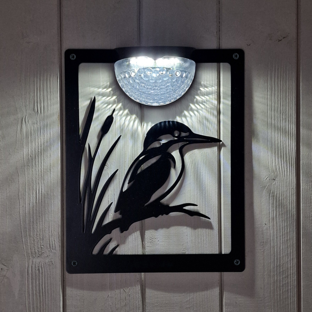 Kingfisher solar plaque lit at night, light fanning down over the cut-out