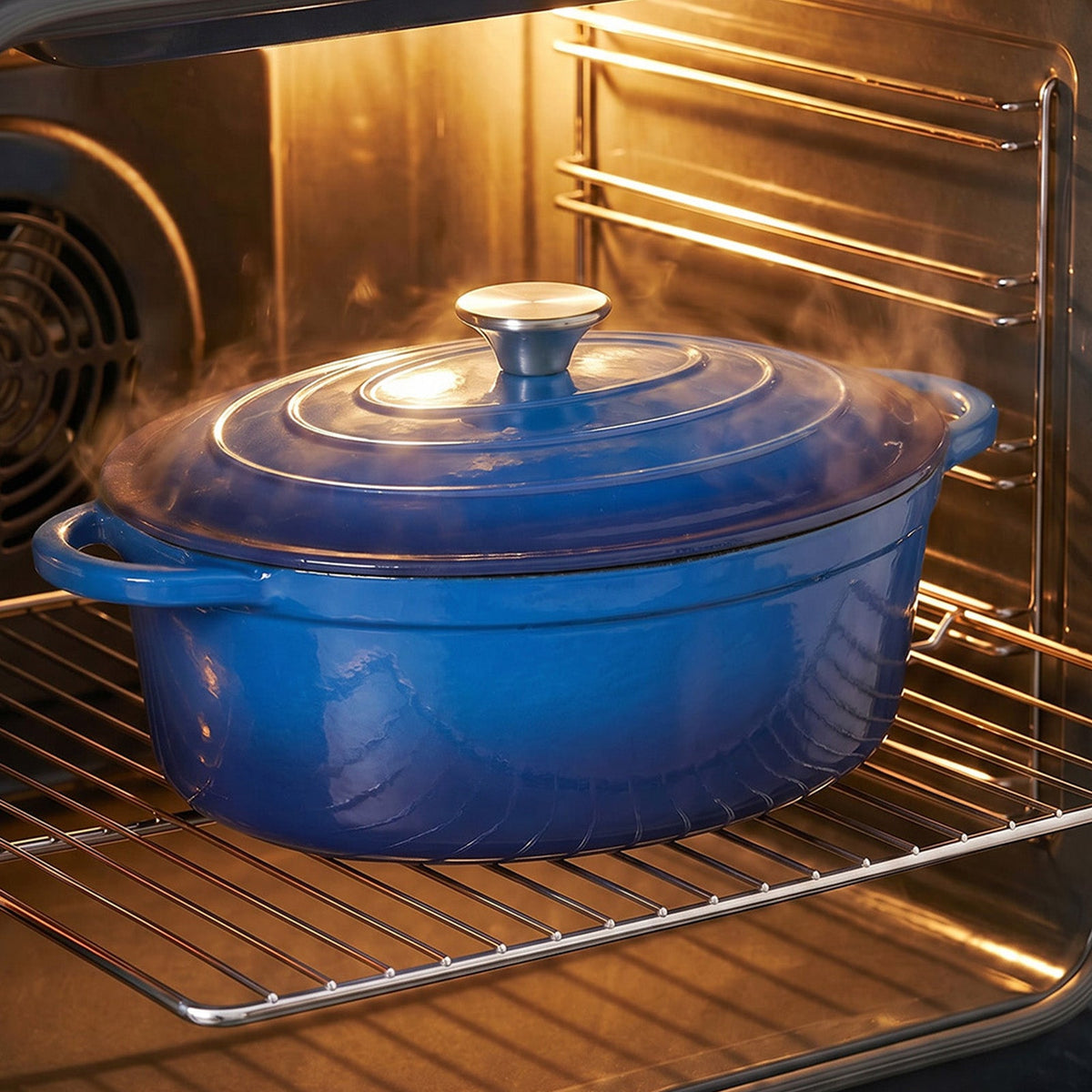 Blue oval enamelled Dutch oven with its lid on, on the rack of a hot oven