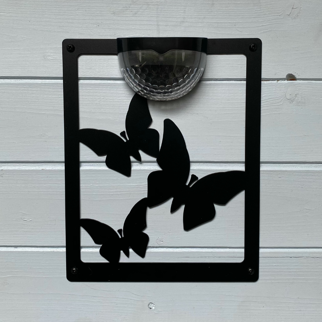 Open three-butterfly cut-out solar plaque on white painted cladding