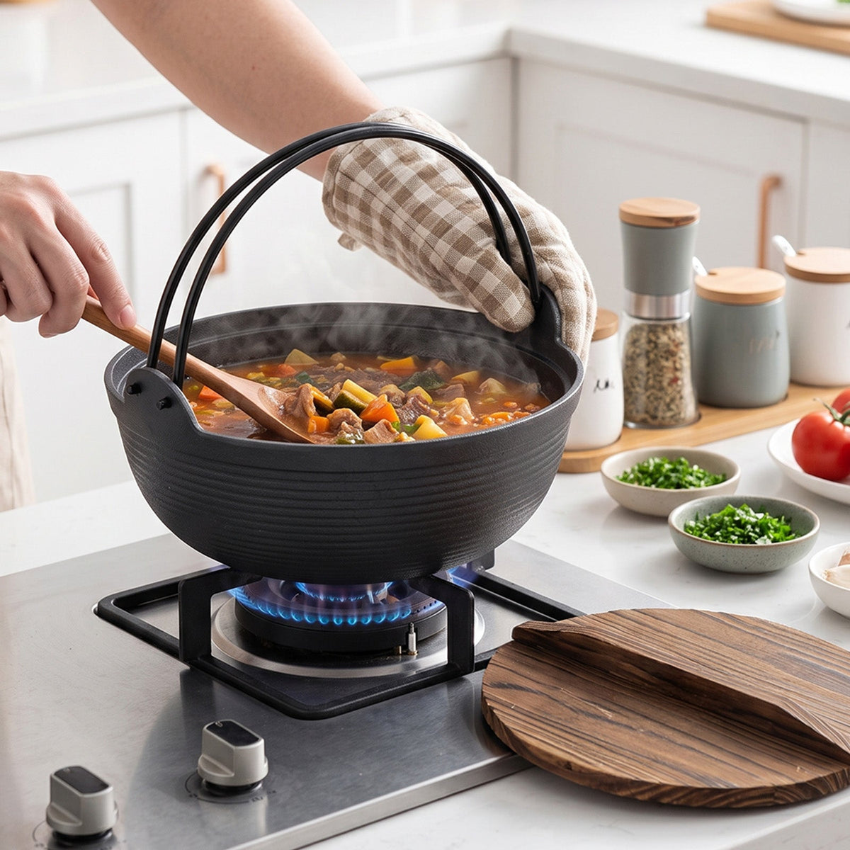 Vegetable stew in the cast iron nabe pot on a gas hob, stirred with a wooden spoon