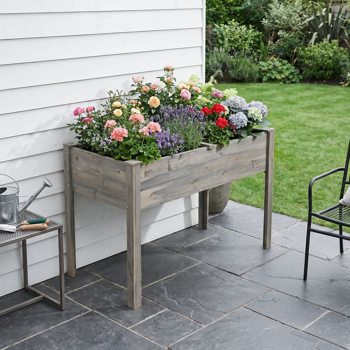 Grey wood elevated planter full of roses and hydrangeas on a slate patio