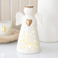 Off-white ceramic angel holding a gold heart, lit from inside through heart and star cut-outs