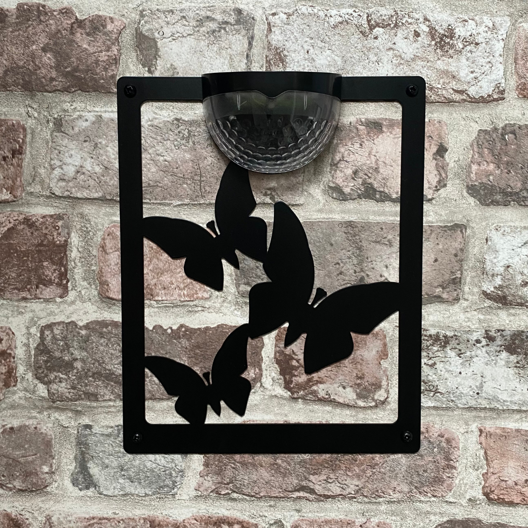 Open three-butterfly cut-out solar plaque on a brick wall