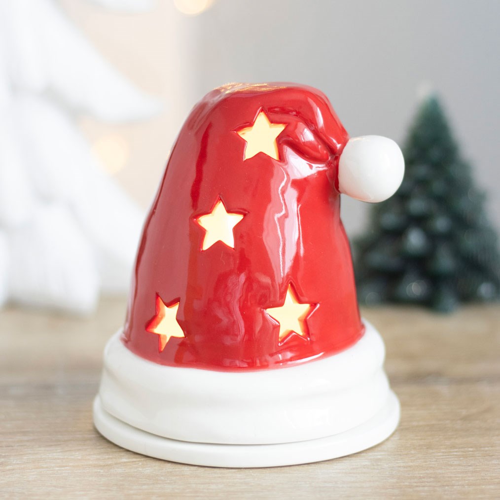 Red and white Santa hat tealight holder glowing through star cut-outs on a wooden table