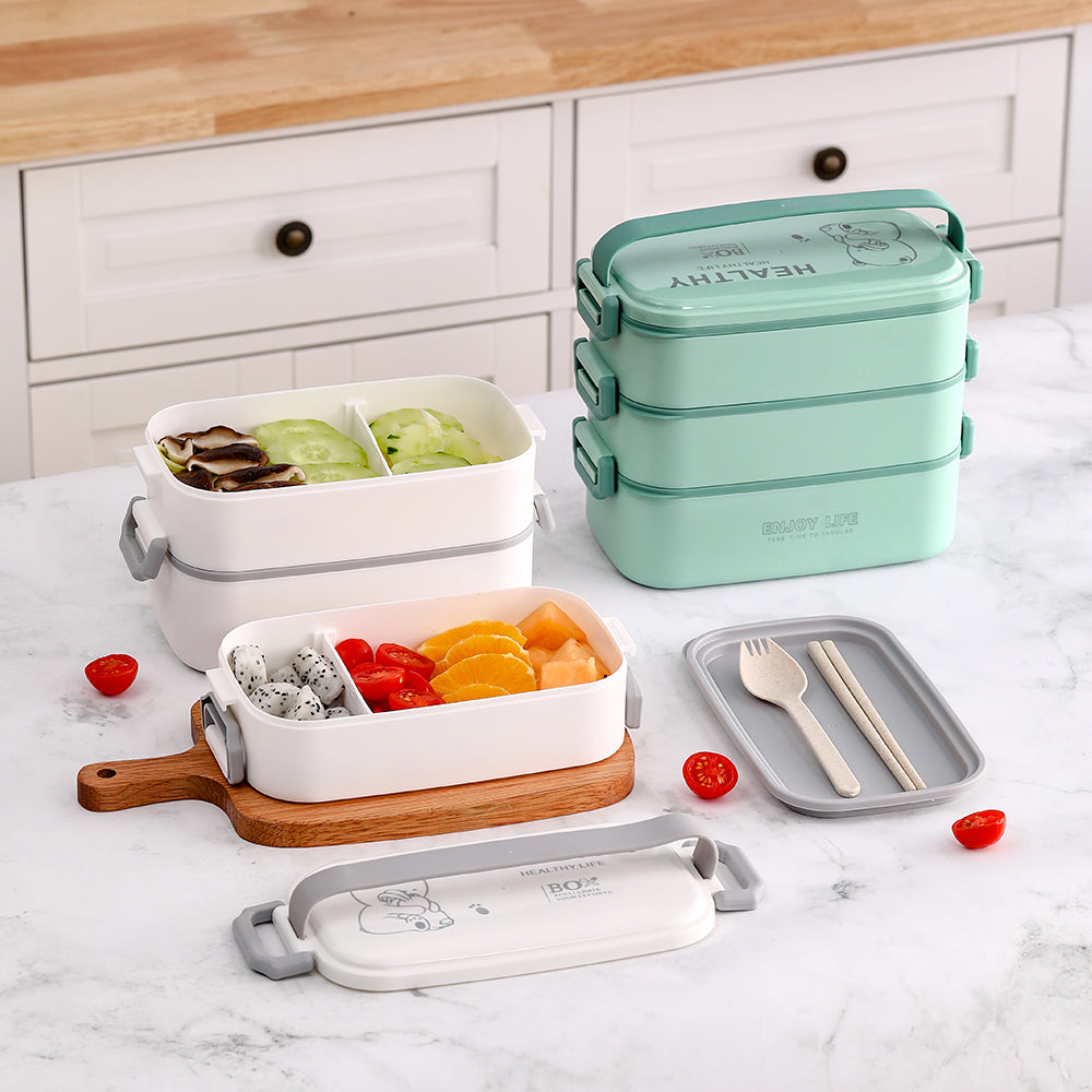 The lunch box opened into tiers filled with food, beside a green version and cutlery