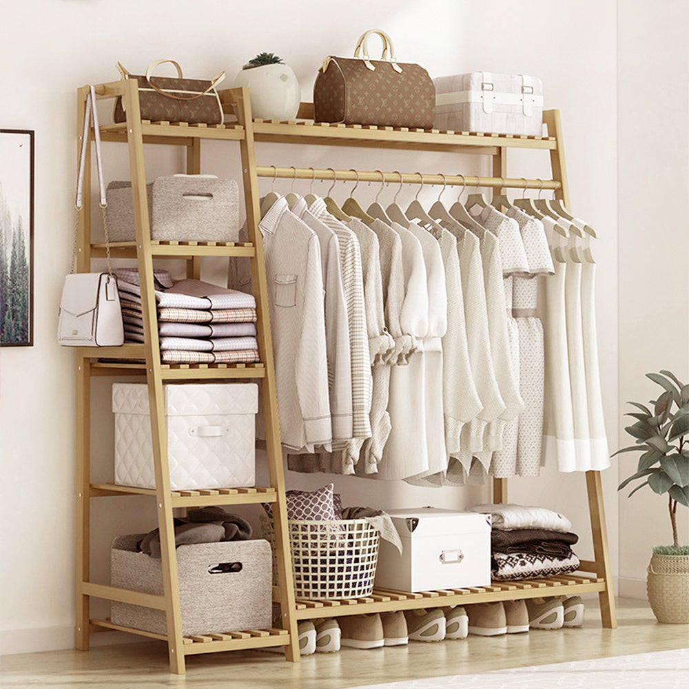 Natural bamboo clothes rack with shirts on the rail, folded clothes on the side shelves and shoes below