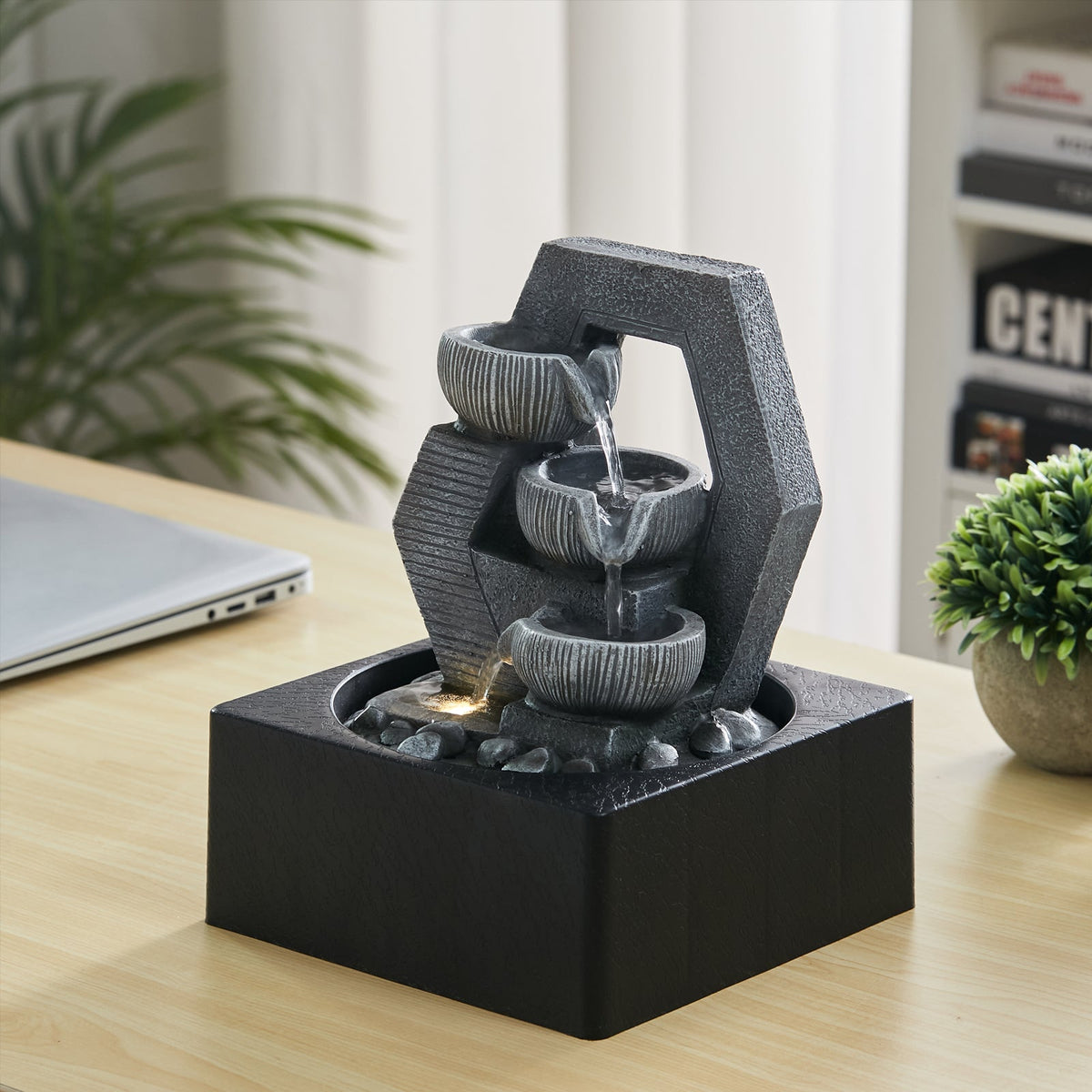 Grey resin cascade fountain with three bowls, lit by its LED, on a wooden desk