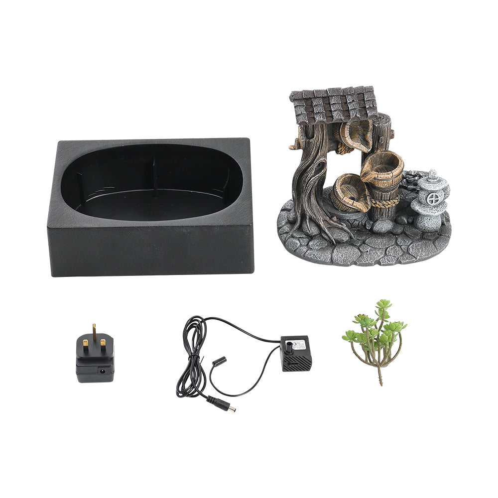 Fountain parts on white: basin, resin scene, pump with cable, plug adapter and small plant