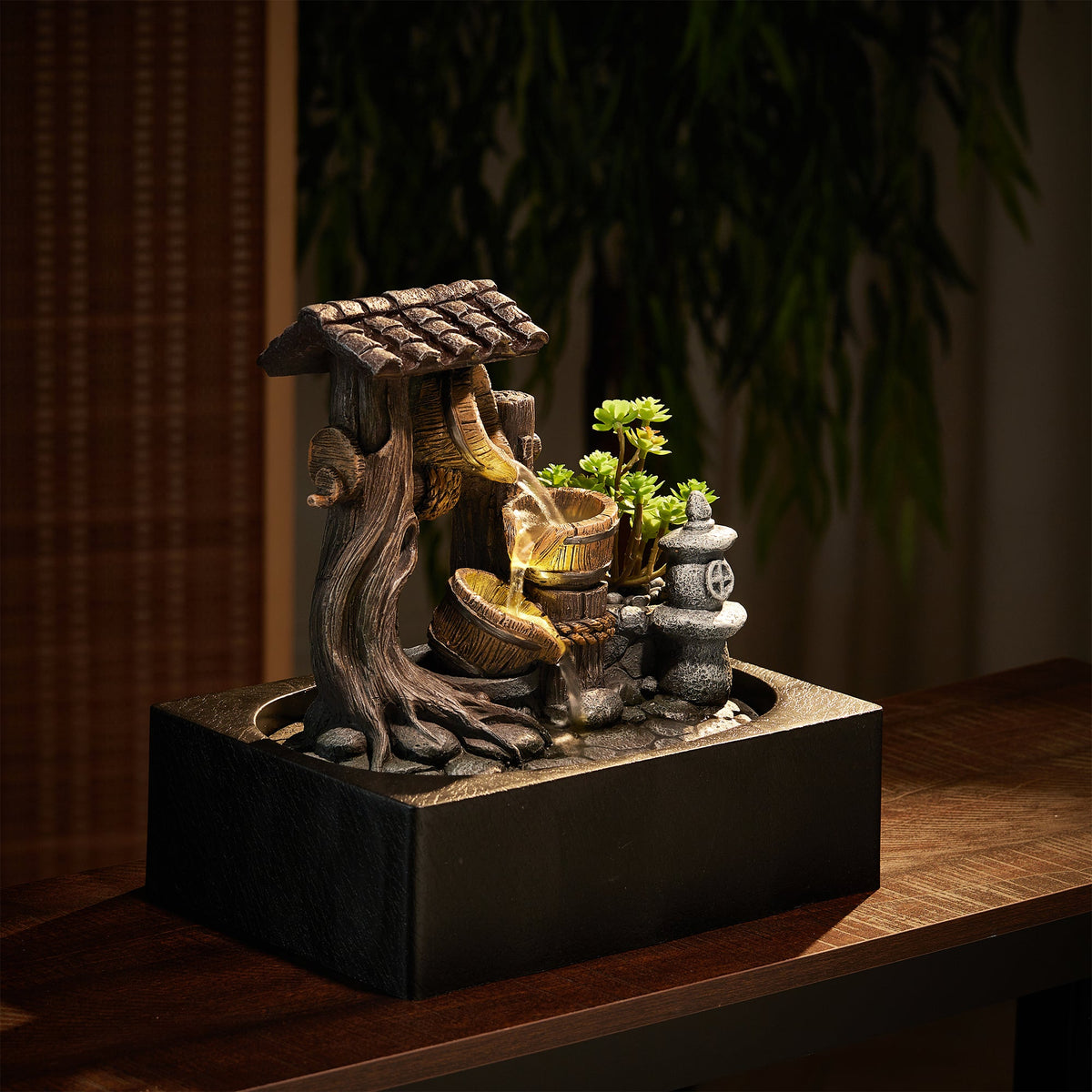 Resin tabletop fountain lit by its LED on a dark wooden sideboard
