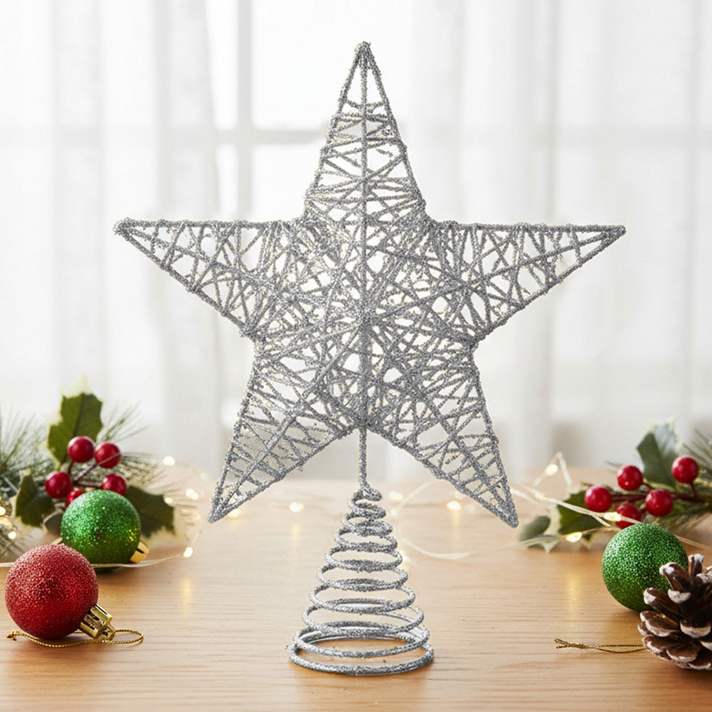 Silver glittered wire star topper on its spiral base on a table with baubles and pine cones