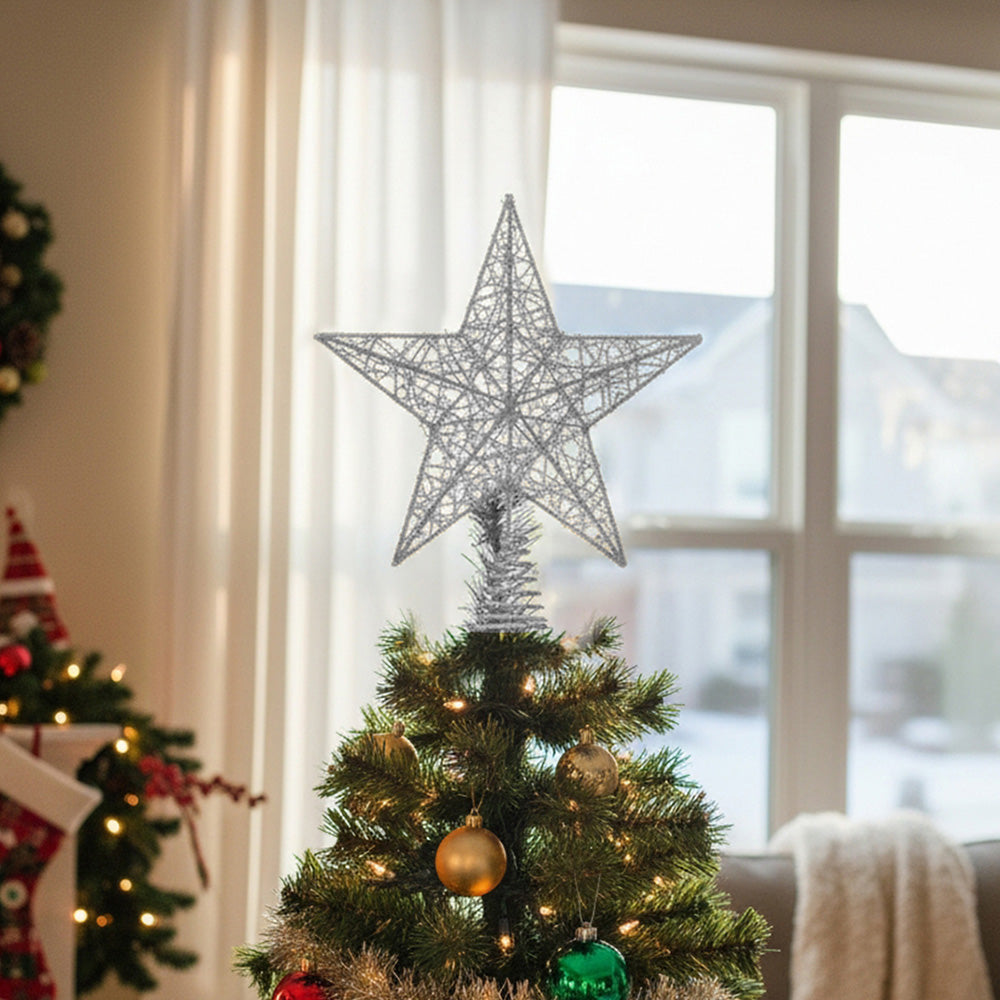 Silver glittered wire star topper on top of a Christmas tree by a window