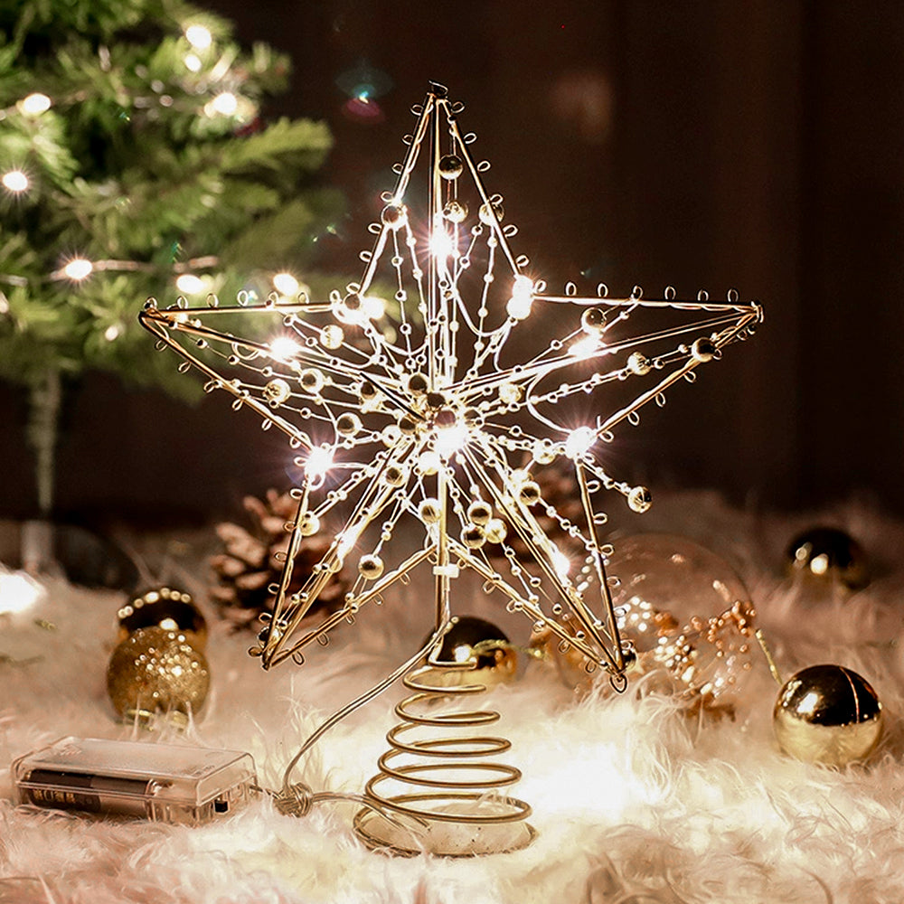 Lit gold wire star tree topper with gold beads on a spiral base, battery box beside it on white faux fur