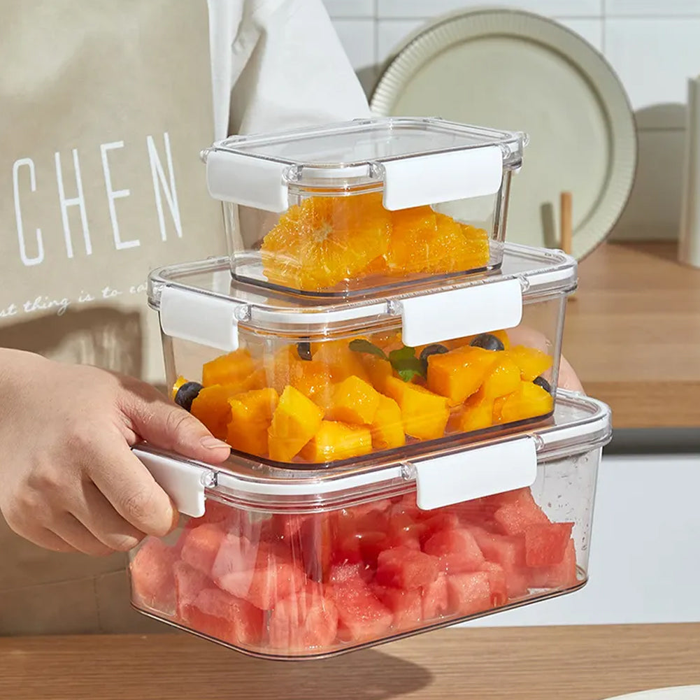 Hands carrying the three stacked clear boxes filled with orange slices, mango and watermelon
