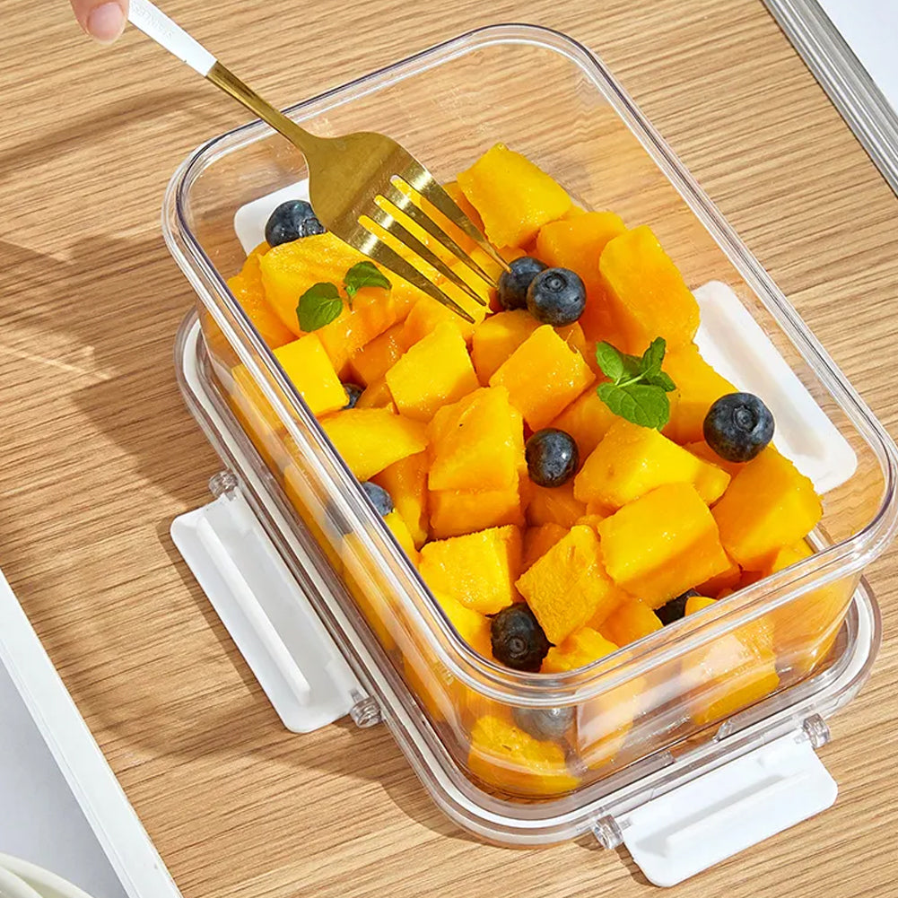 Close view of a clear box of mango and blueberries with its white-clipped lid underneath