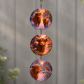 Three round glass discs with winter Highland Cow pictures hanging on a chain against a grey wall