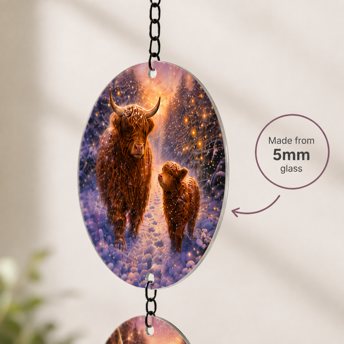 Close-up of one glass disc with a Highland Cow and calf in snow, with a small note that it is made from 5 mm glass