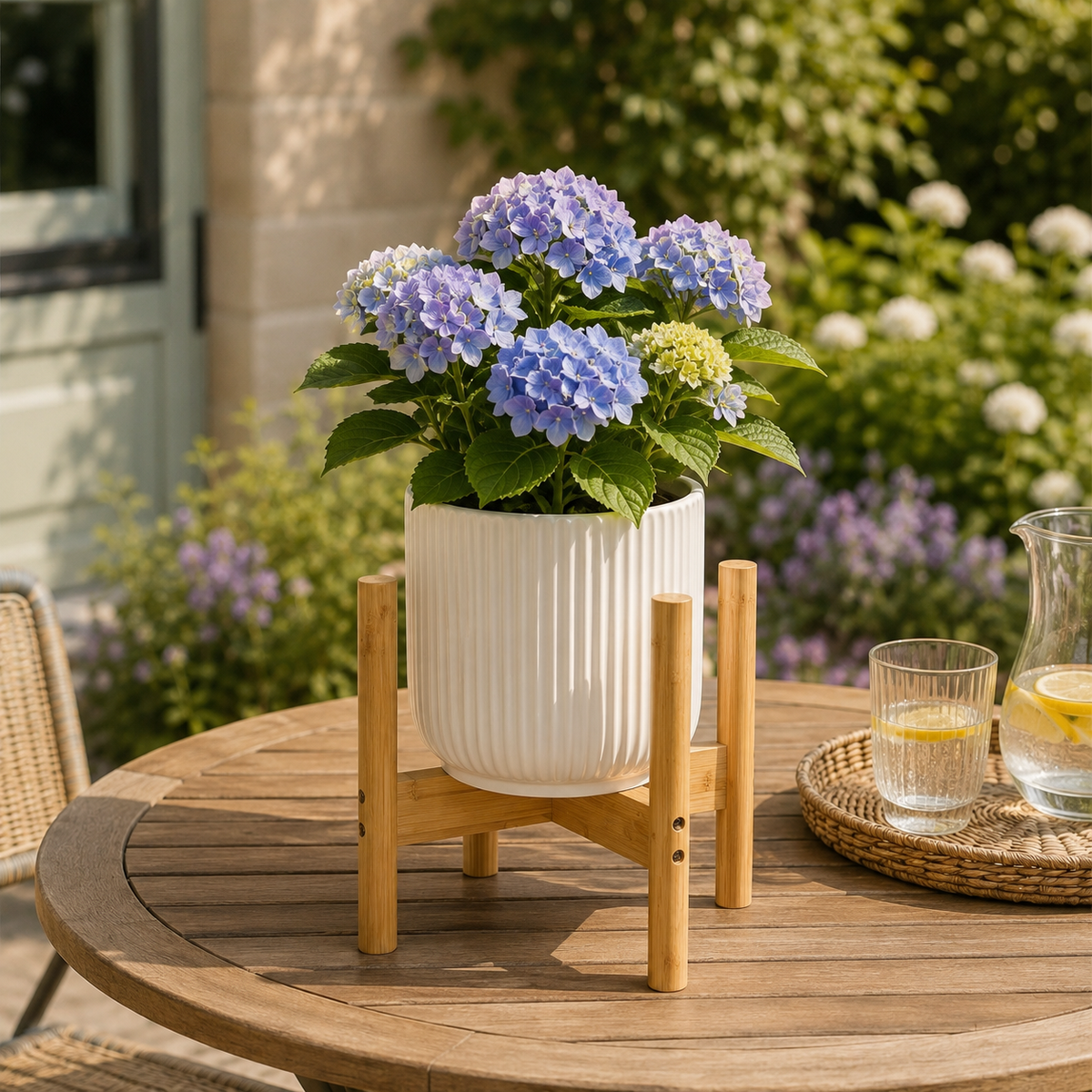 Bamboo pot stand with a white pot of blue hydrangeas on a round garden table