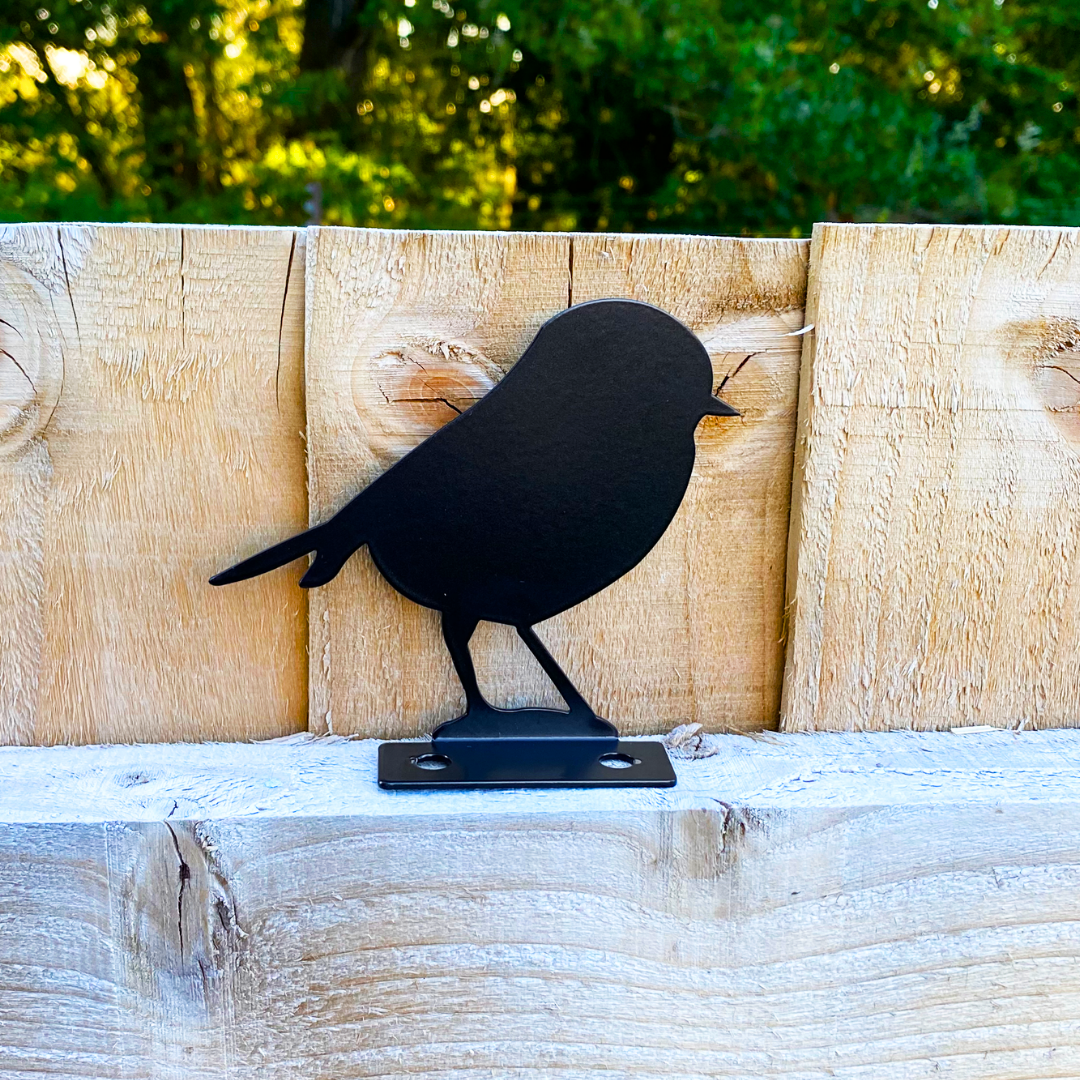 Black steel robin topper on a wooden fence rail