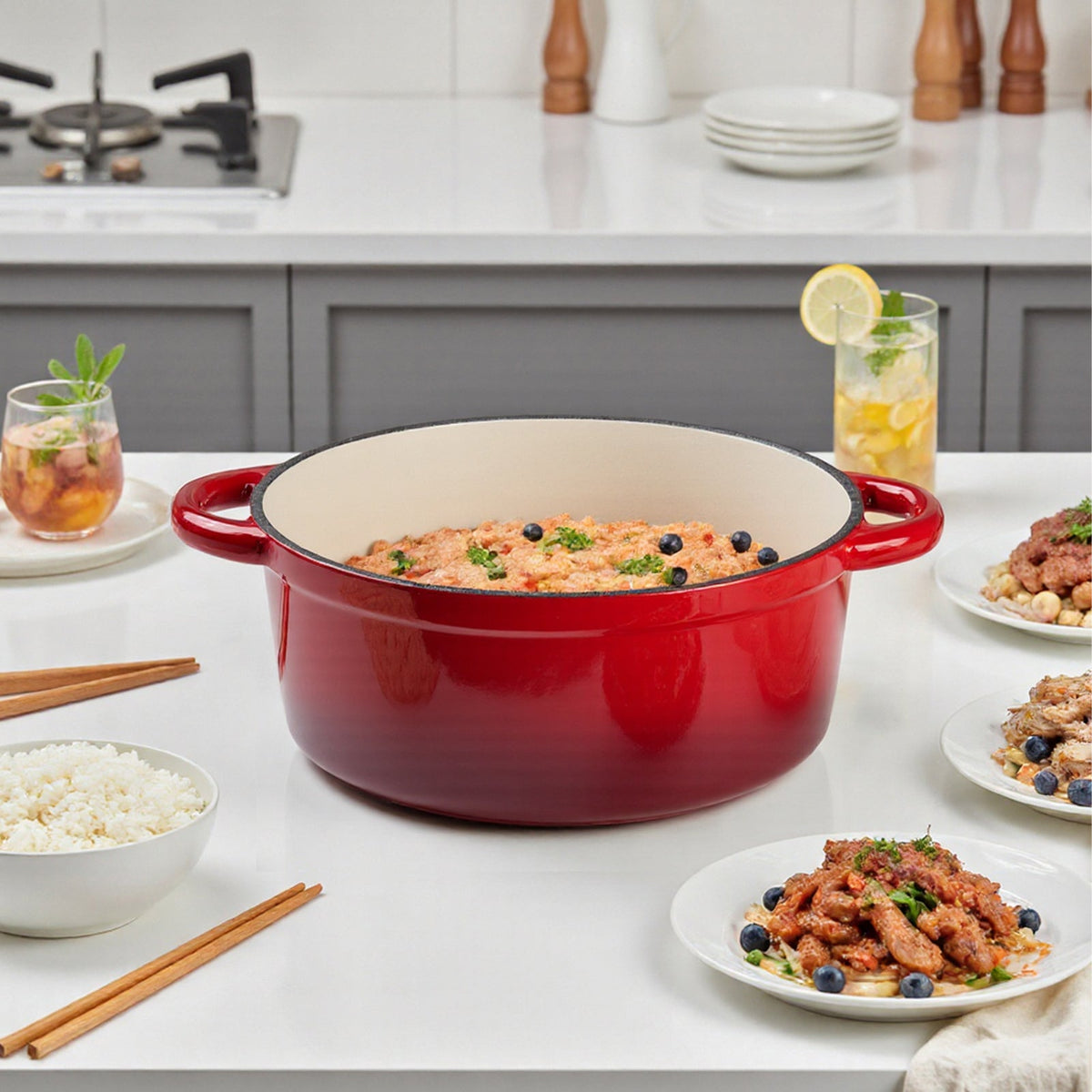 Red enamelled Dutch oven filled with rice and vegetables on a white kitchen table with plated dishes