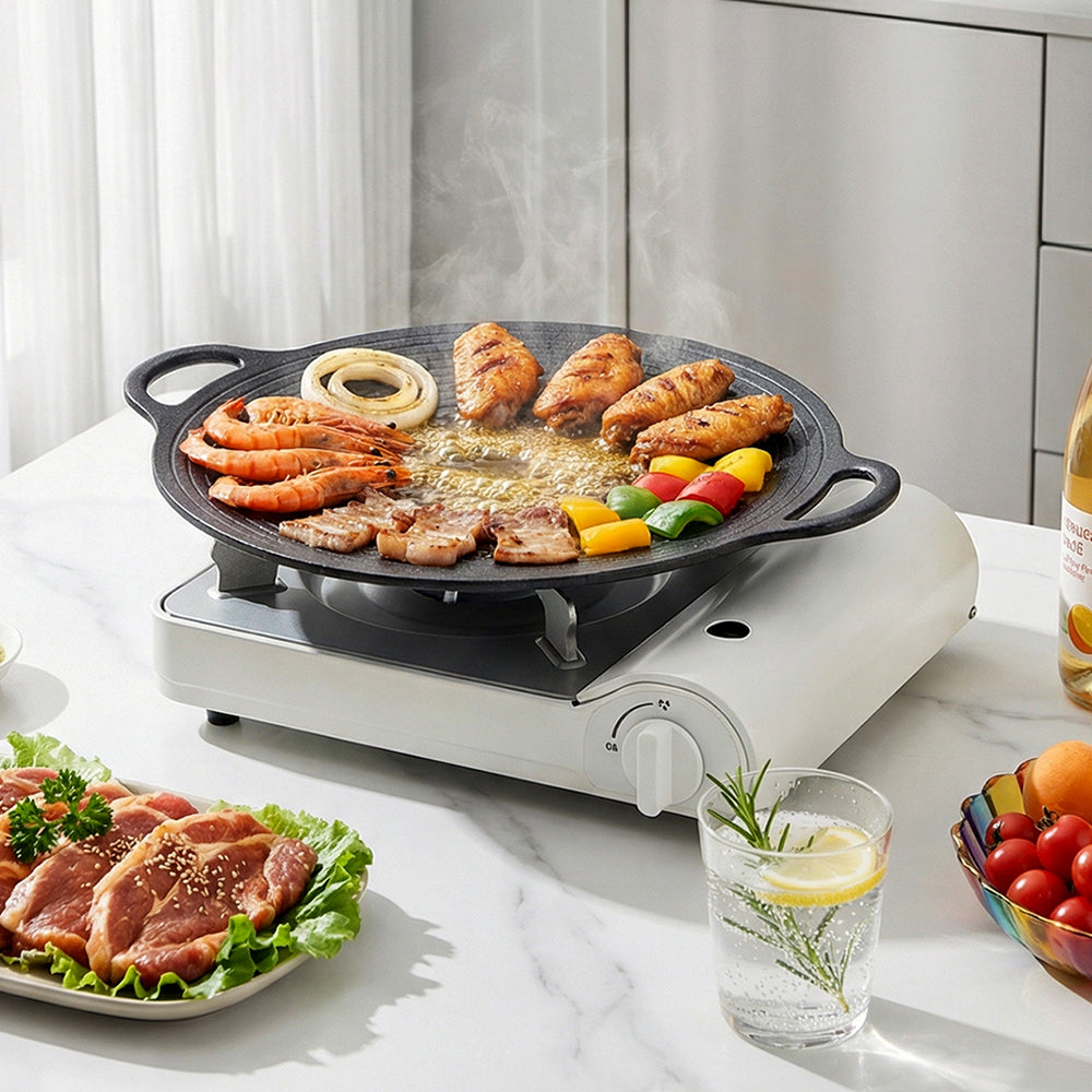 Round grill pan on a white portable gas stove with prawns, chicken, pork and peppers