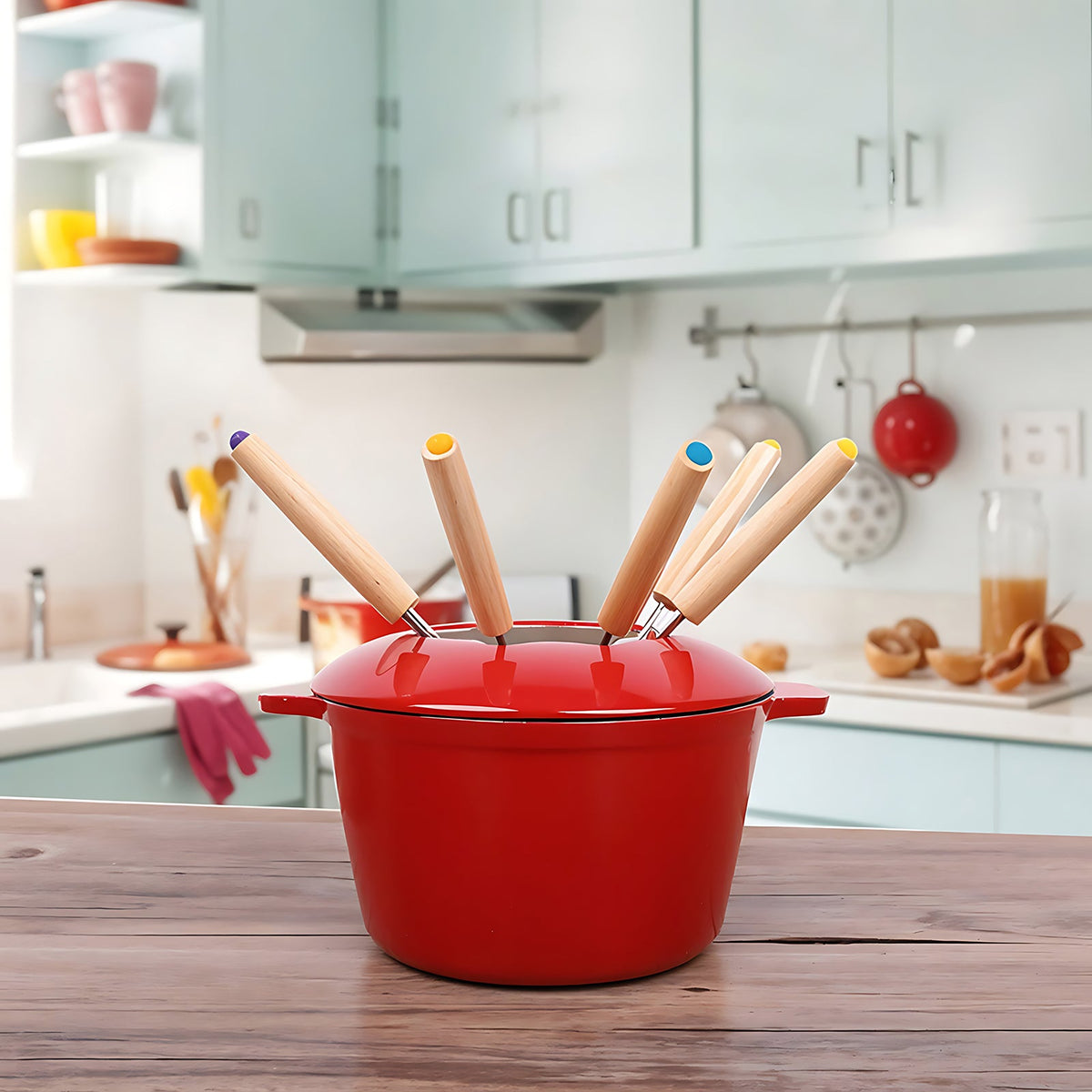 Red enamelled fondue pot with six forks on a wooden kitchen table