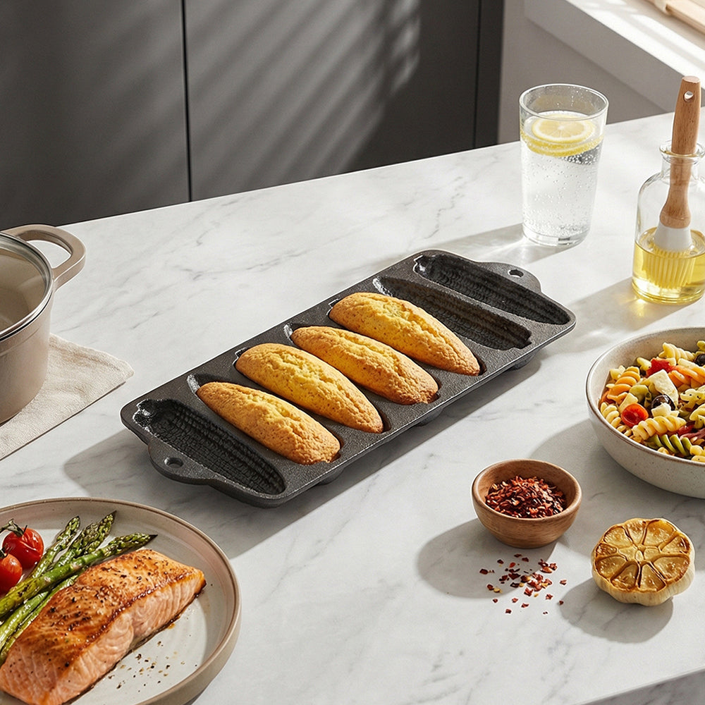 Cast iron corn cob pan with baked corn sticks on a marble table beside a salmon plate