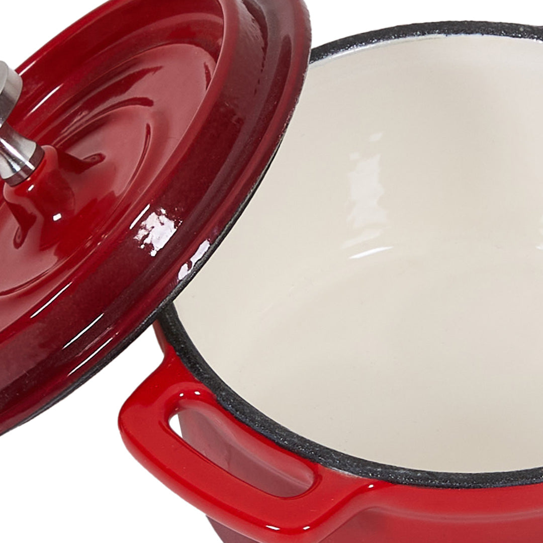 Close-up of the red pot with its lid lifted, showing the cream enamel inside