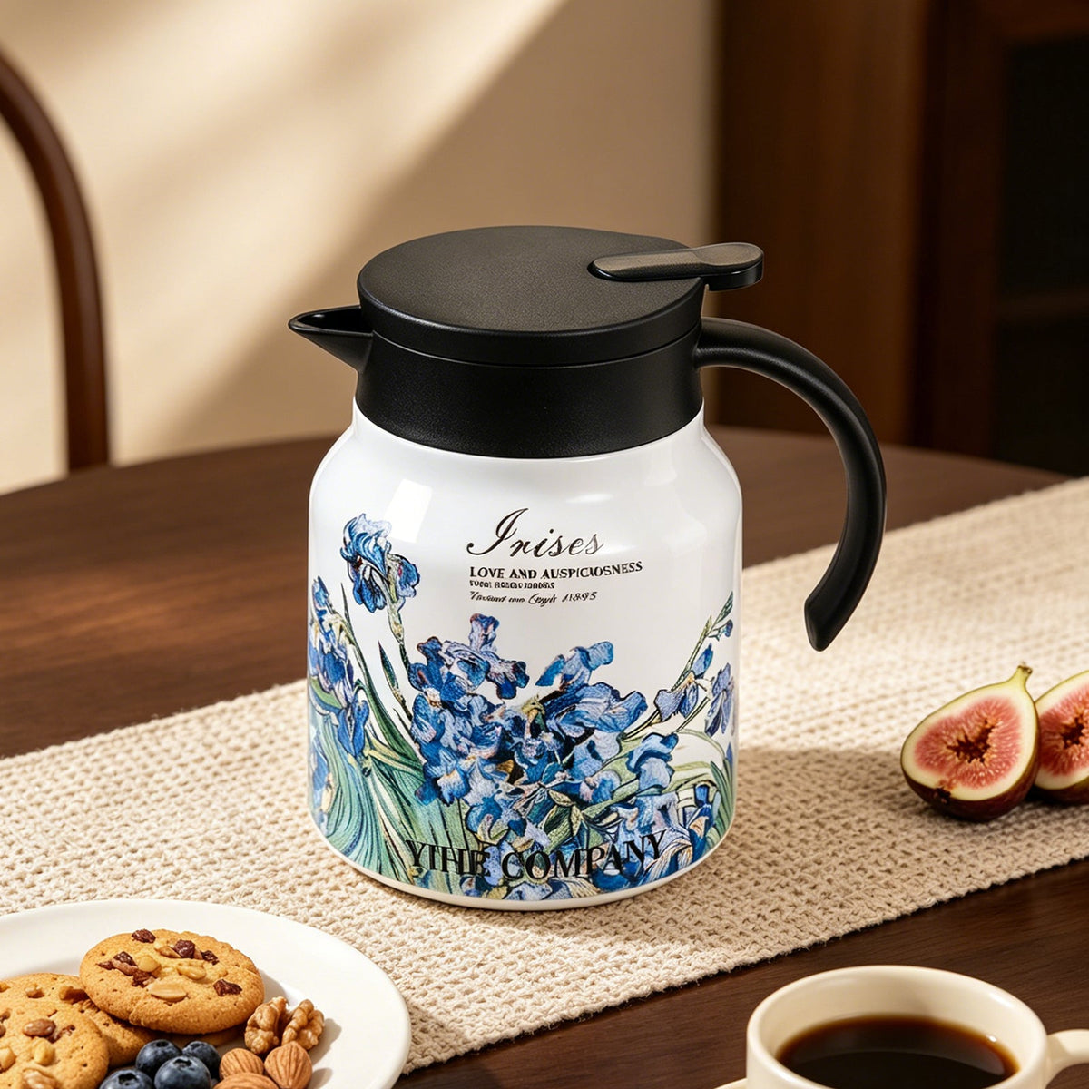 White thermal teapot printed with blue irises on a table runner with coffee and biscuits