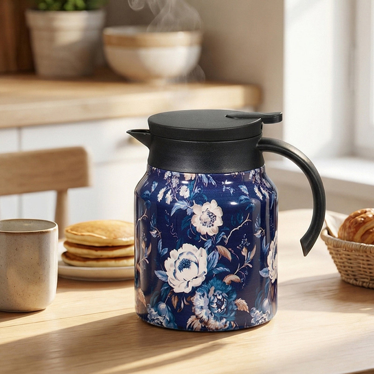 Thermal teapot with white flowers on a navy print, on a kitchen table with pancakes and a mug