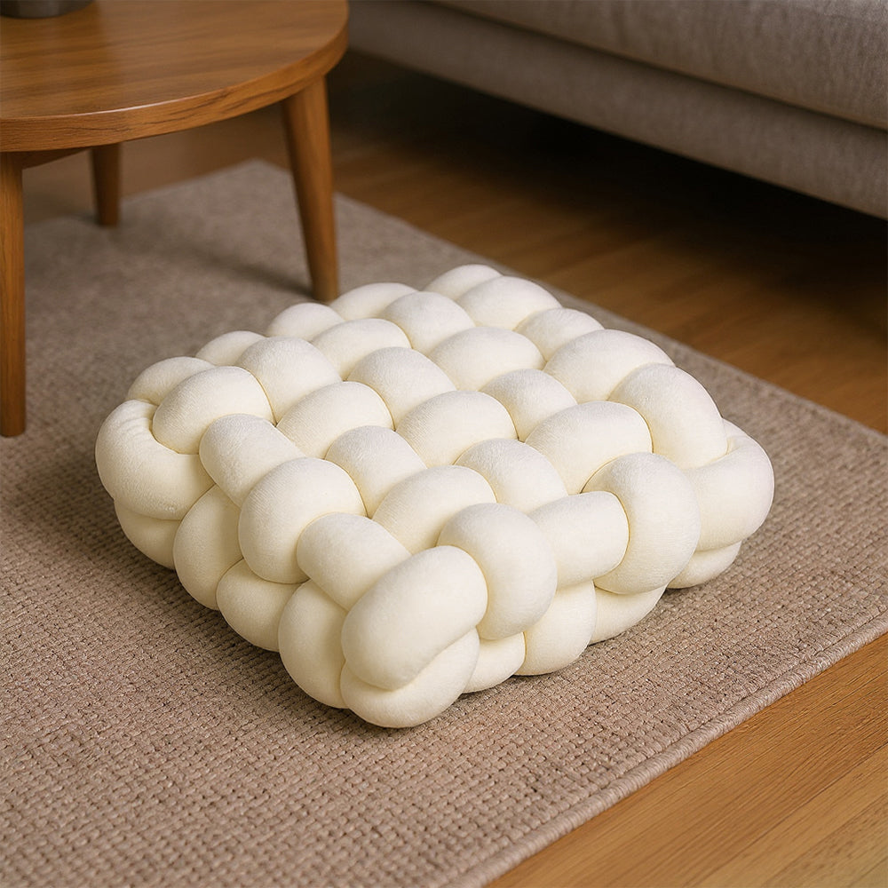 Cream knotted plush seat cushion on a brown rug on a wooden floor