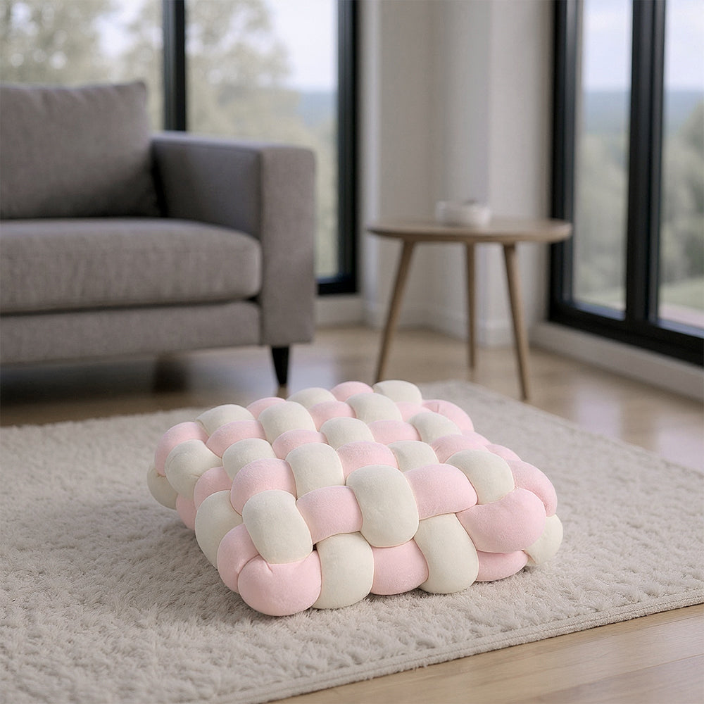 Cream and pink knotted seat cushion on a pale rug in a living room