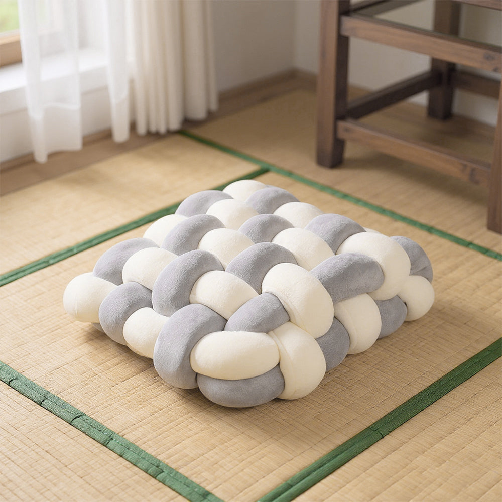 Cream and grey knotted seat cushion on a woven floor mat
