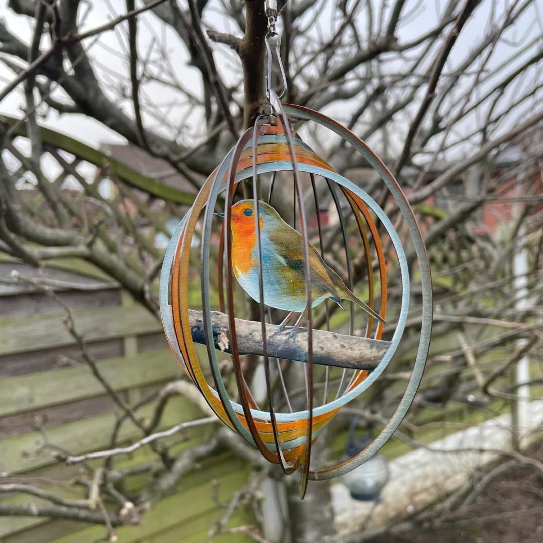 Robin wind spinner hanging from a bare tree branch in a garden