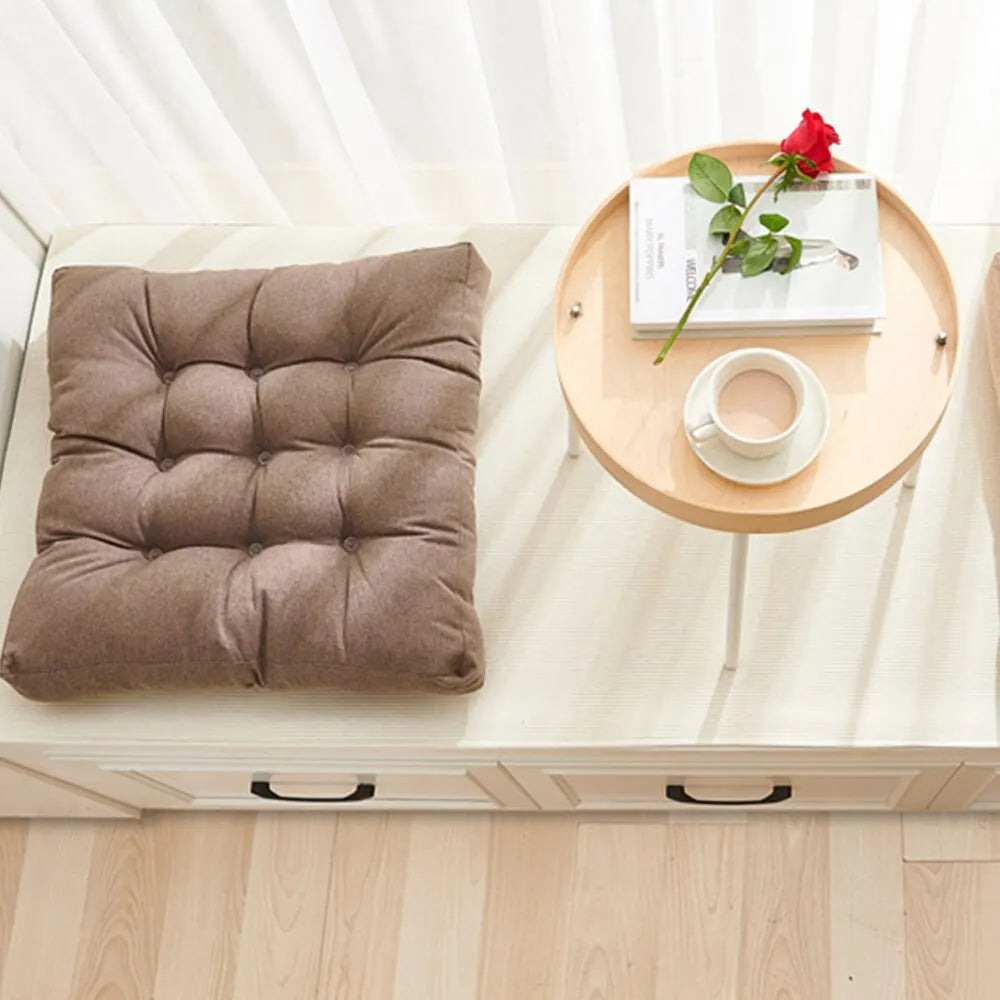 Greyish-brown tufted square cushion on a white bench beside a small round side table