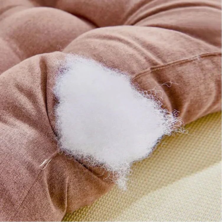 Close-up of a tufted cushion opened at one corner showing white fibre filling