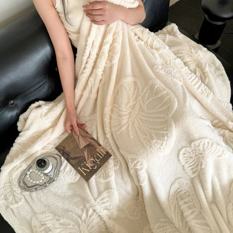 Cream butterfly fleece blanket draped over a black sofa with a tray and a book