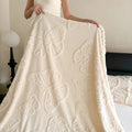 Cream coral fleece blanket held open to show the raised butterfly pattern across it