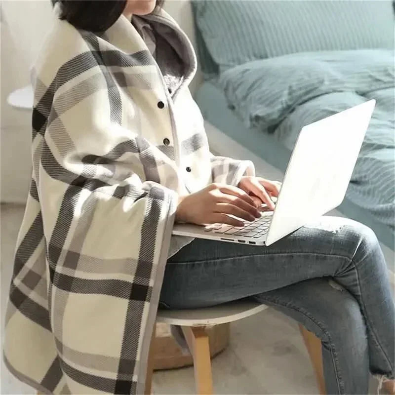 A woman at a laptop wearing a cream and grey plaid throw as a shawl