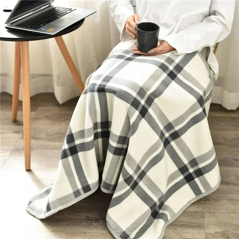 Cream and grey plaid throw spread over a seated person's lap beside a laptop