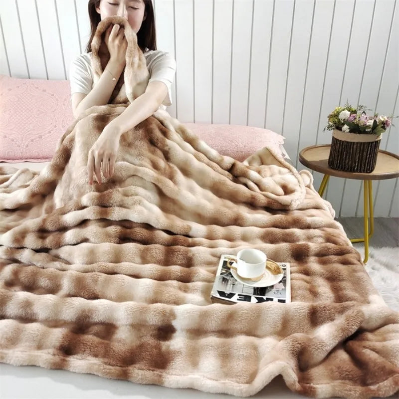 A woman sitting on a bed with the plush striped blanket over her knees
