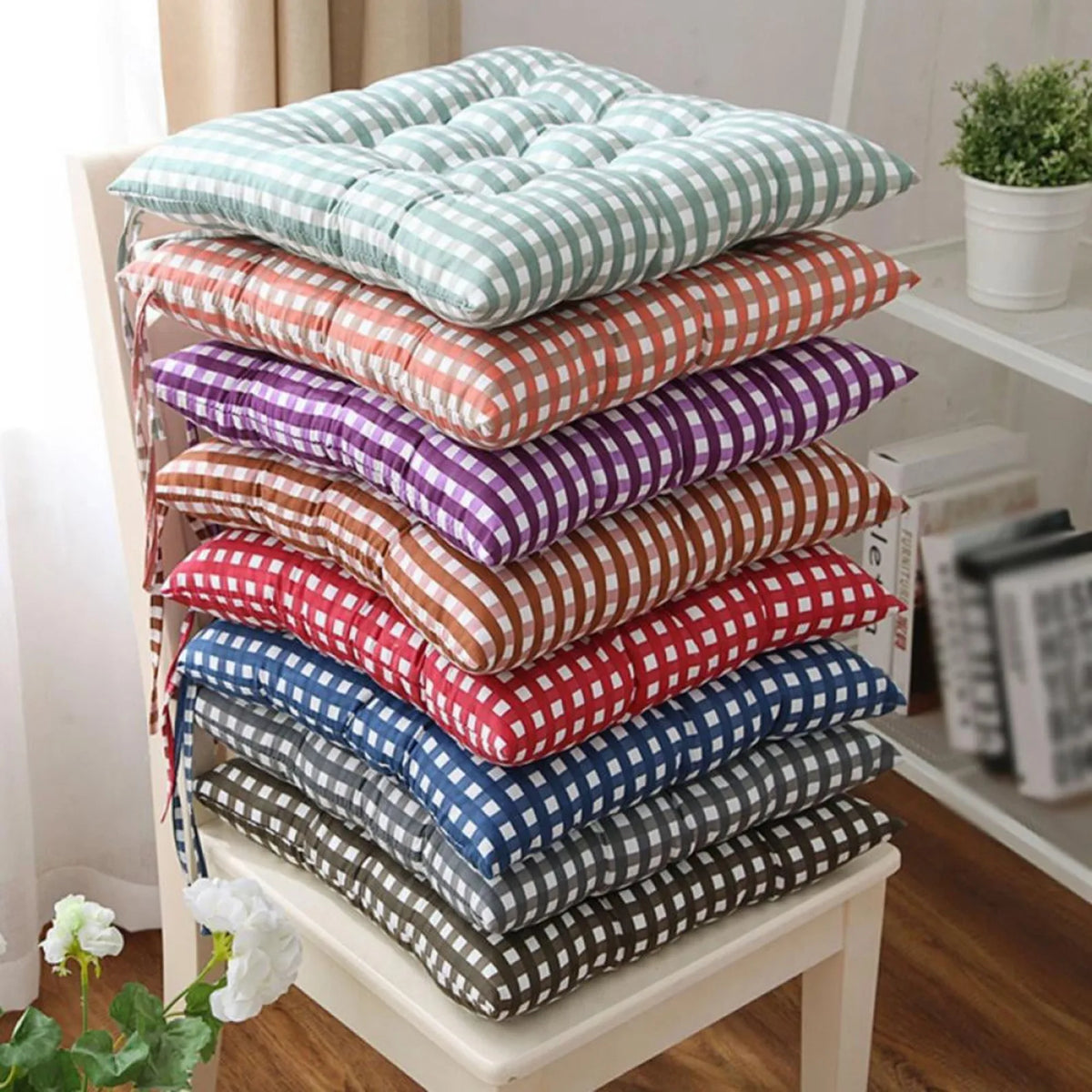 A stack of gingham seat cushions in several colours on a white chair