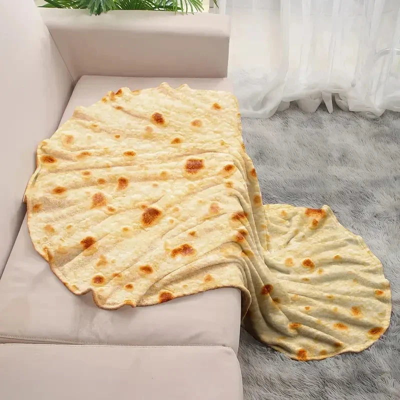 Tortilla-print round fleece blanket draped over a pale pink sofa onto a grey fur rug