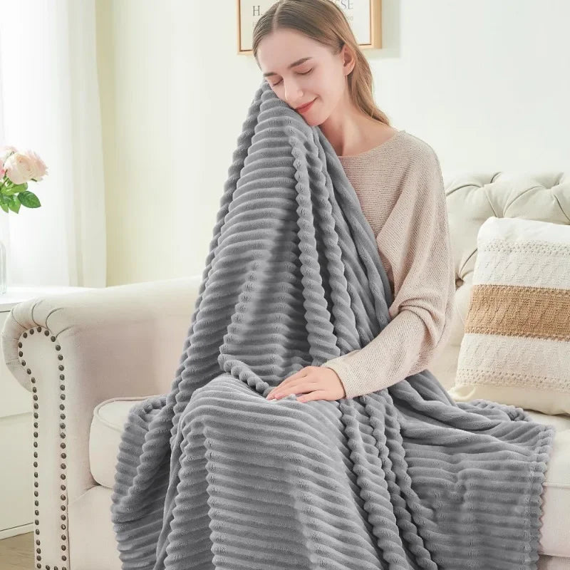 A woman on a sofa wrapped in the light grey ribbed throw