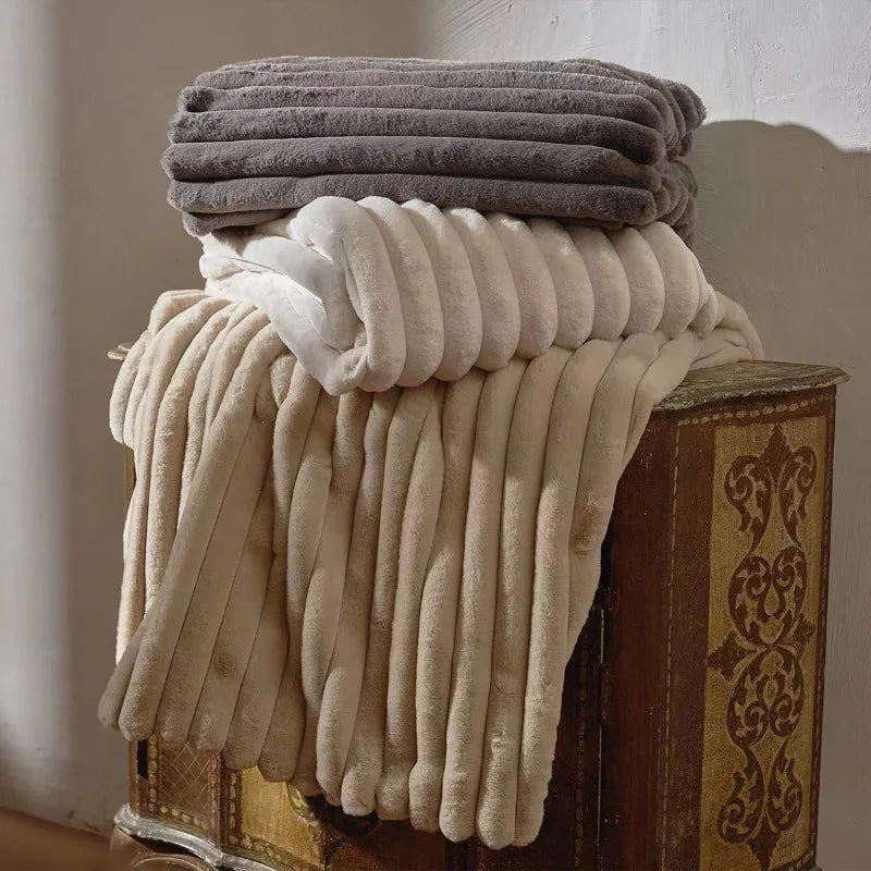 Beige and grey ribbed throws folded and stacked on a wooden chest