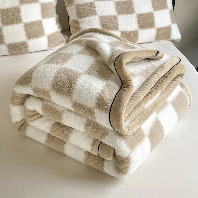 Khaki and white checked fleece blanket folded on a bed with matching checked pillows