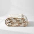 Khaki and white checked coral fleece blanket rolled up on a white background, bound edge visible