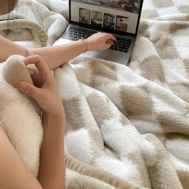 Hands on the soft checked fleece blanket beside an open laptop